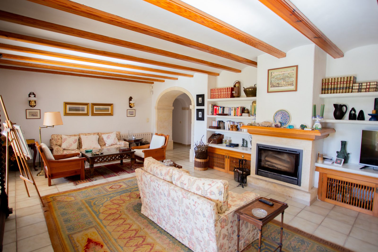 A cozy living room with exposed beams and a fireplace in a 4-bedroom villa in Javea - The Estates