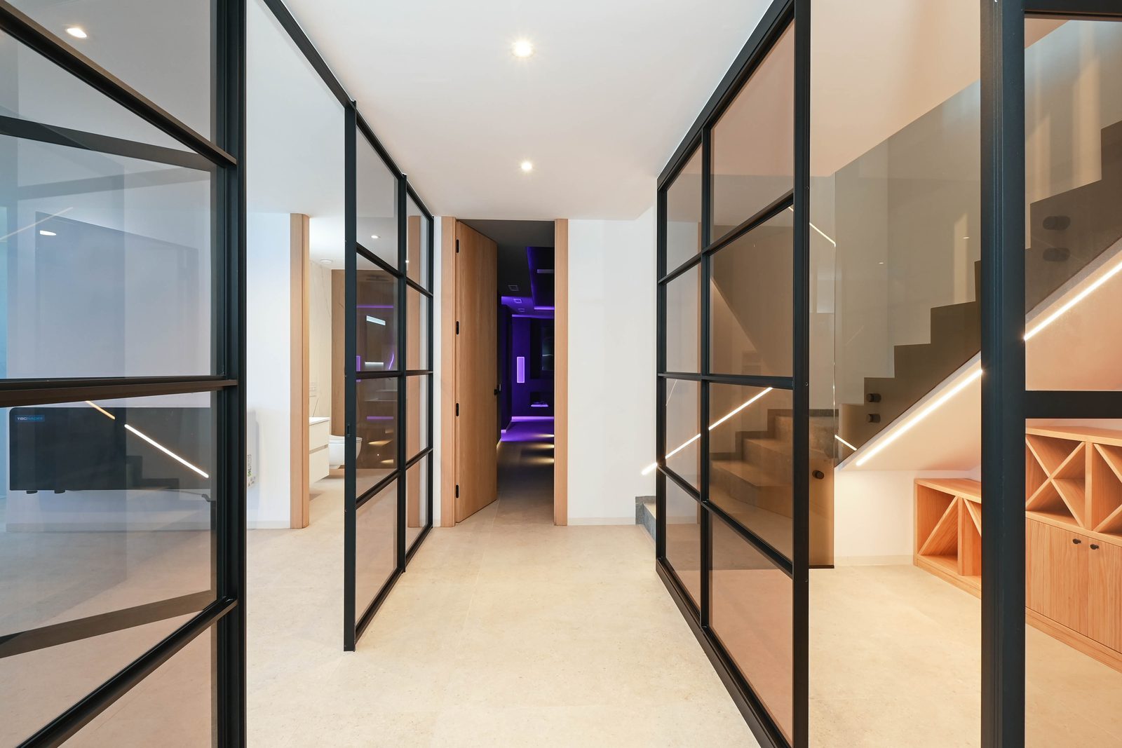 Modern hallway with glass partitions, illuminated staircase and purple-lit room in a 4-bedroom villa in Benissa - The Estates