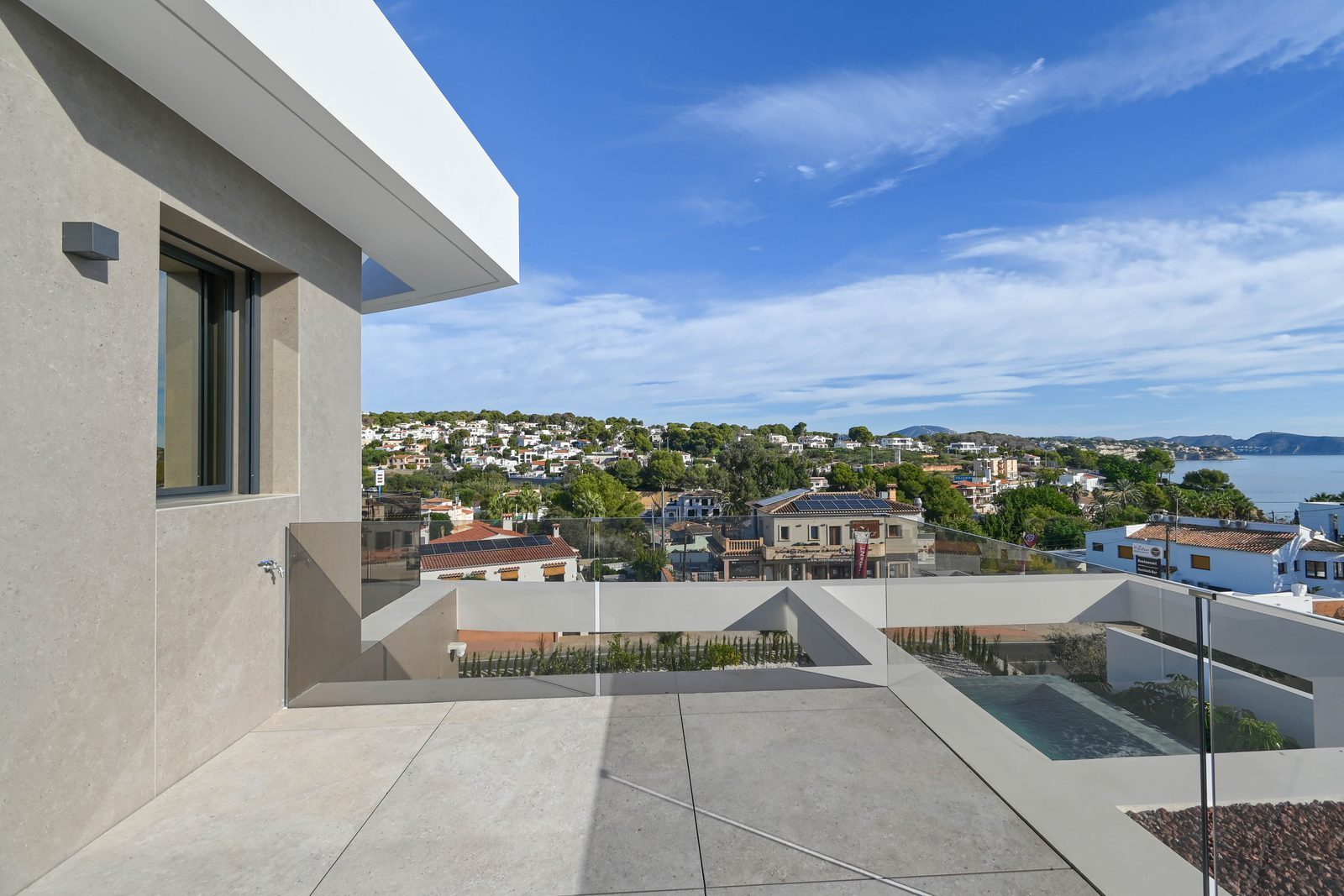 Modern terrace with glass railings, pool and sea views of La Fustera, from a 4-bedroom villa in Benissa - The Estates