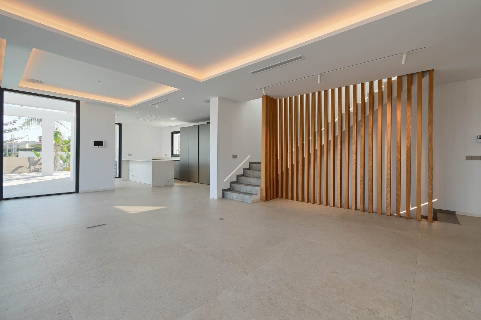 Modern open-plan living area with kitchen, staircase and timber slat partition of a 4-bedroom villa in Benissa - The Estates