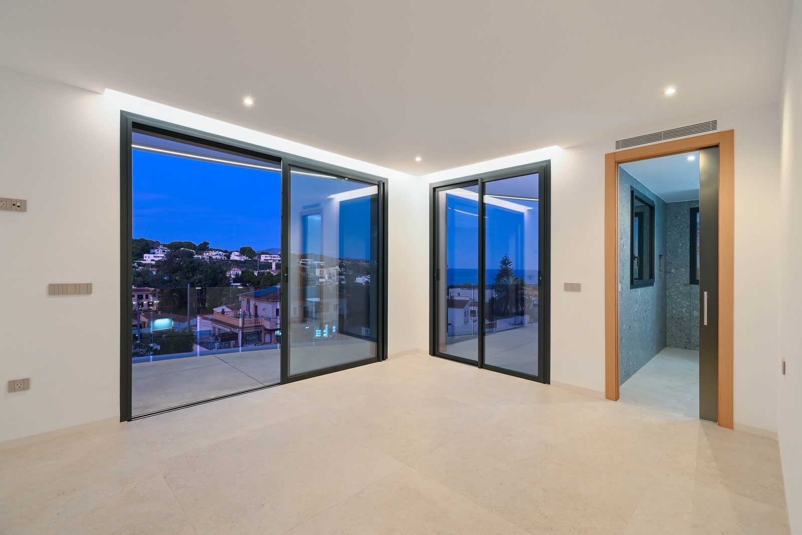 Bright modern room with floor-to-ceiling glass doors opening to a terrace and sea views in La Fustera, of a 4-bedroom villa in Benissa - The Estates
