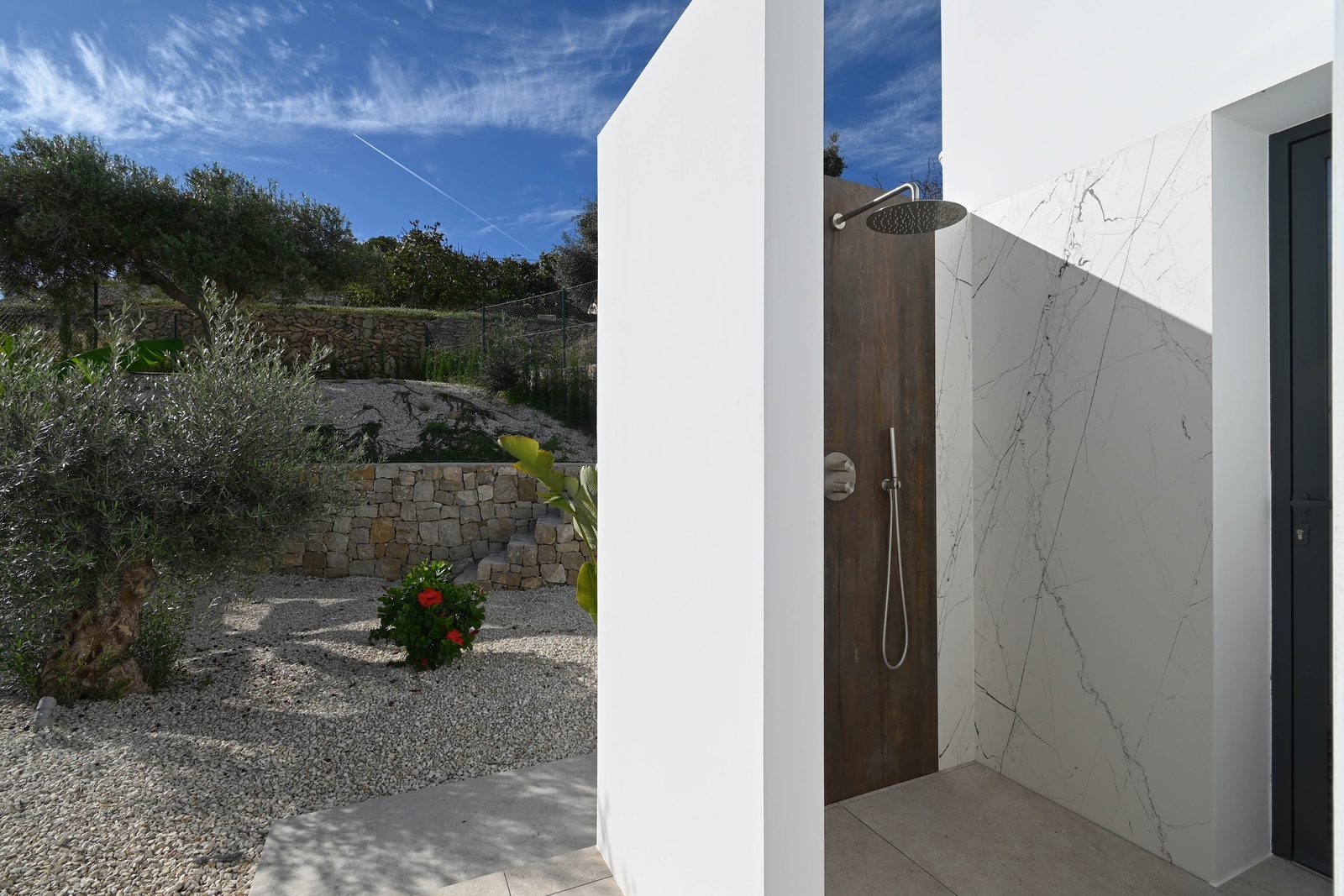 Outdoor shower beside a landscaped garden of a