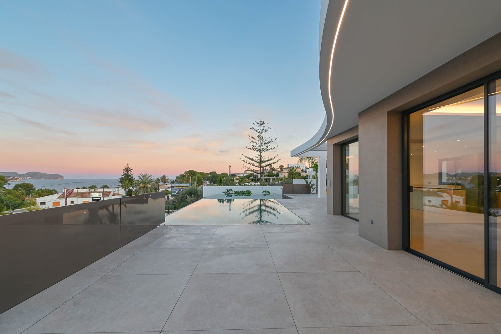 Modern villa terrace with infinity pool and sea views at sunset in La Fustera, Benissa, of a 4-bedroom villa in Benissa - The Estates