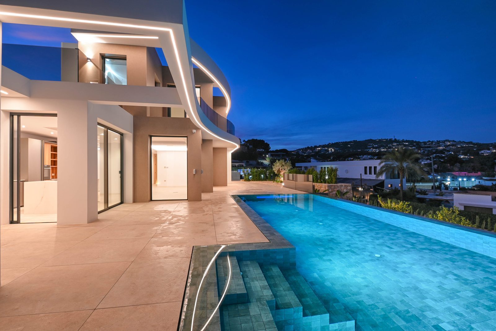 Modern villa exterior with illuminated infinity pool and panoramic sea views at dusk in La Fustera, Benissa - The Estates