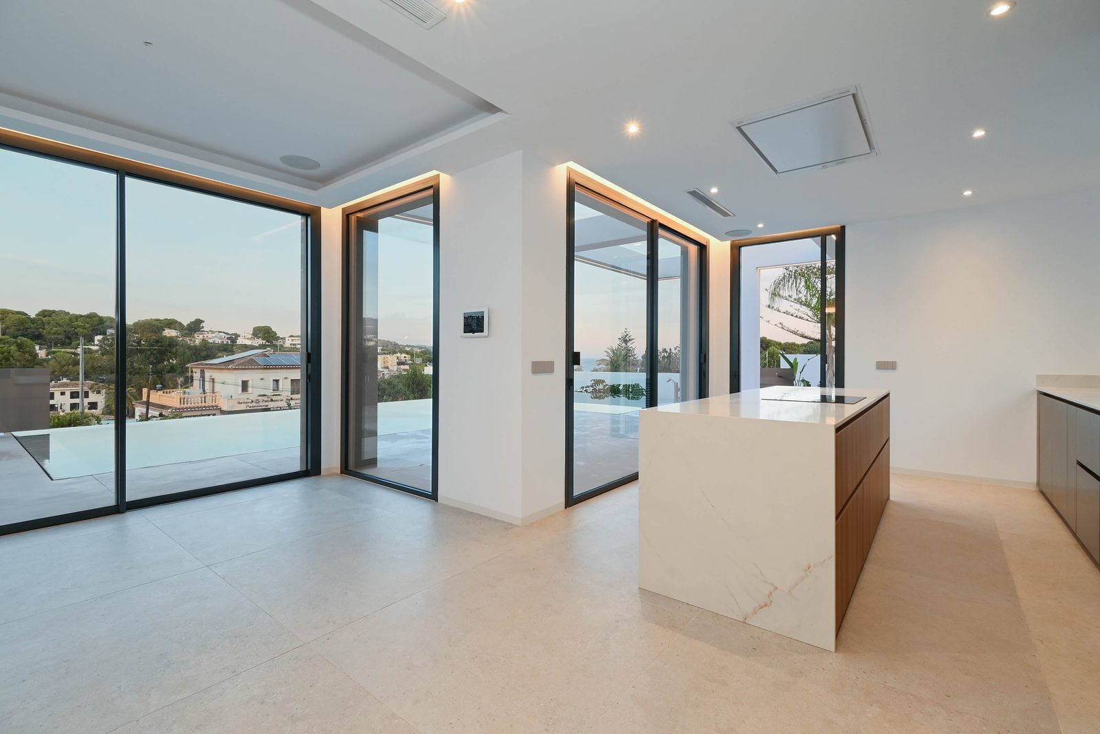 Modern kitchen with island and sea views through glass doors in a 4-bedroom villa in Benissa - The Estates