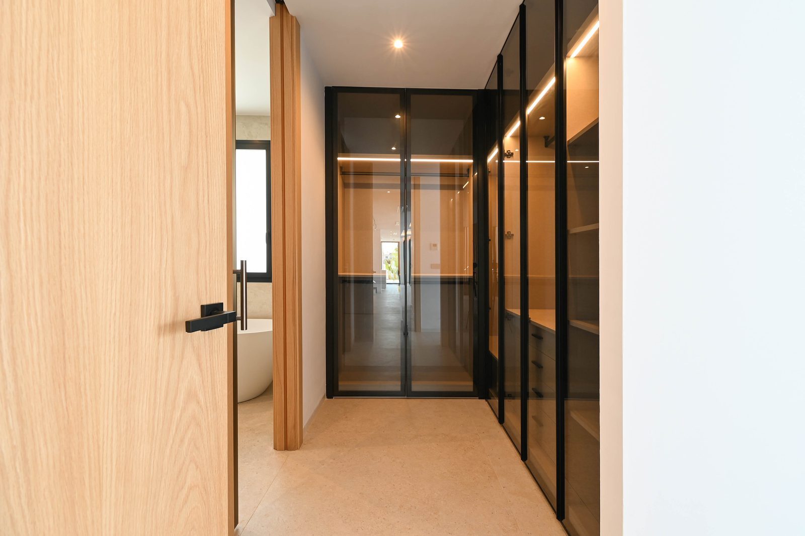 Modern dressing room with illuminated glass-front wardrobes and ensuite glimpse of a 4-bedroom villa in Benissa —