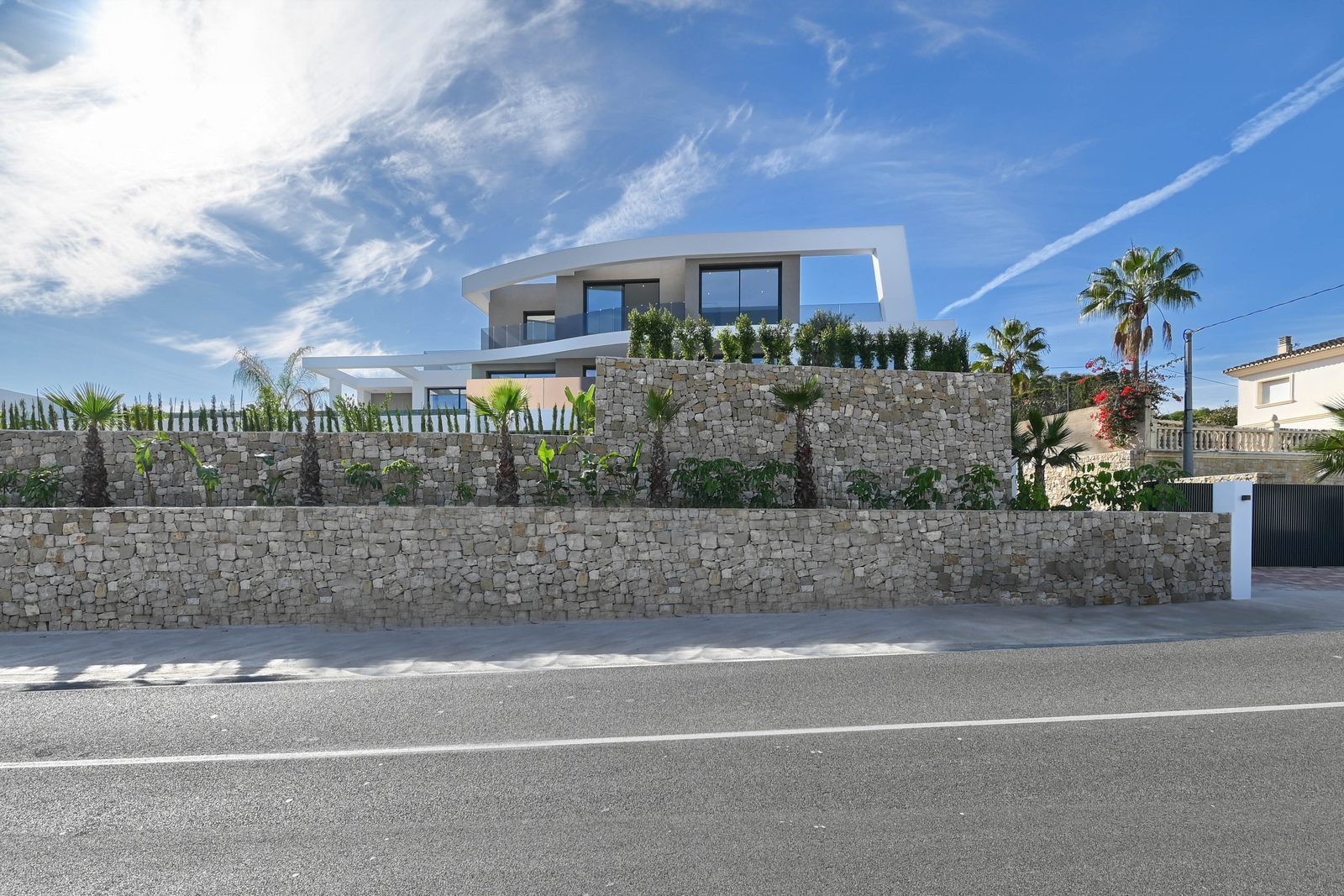 Modern exterior of a 4-bedroom villa in Benissa with stone walls, palms and balconies