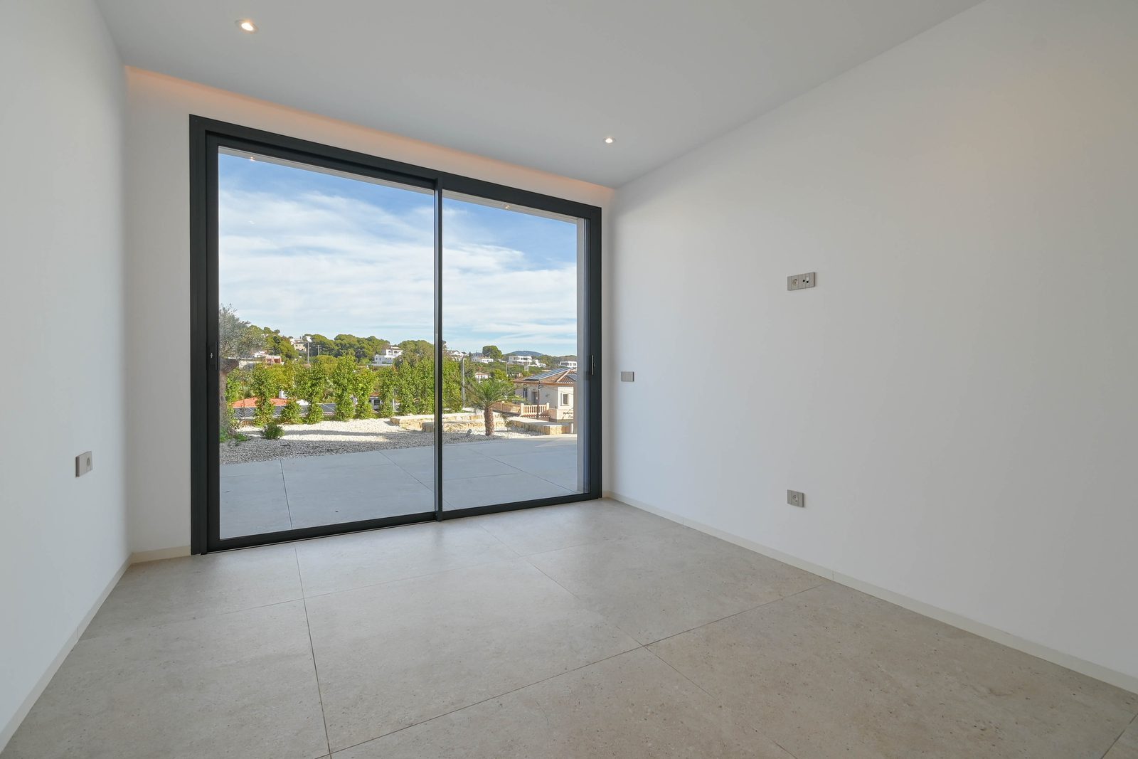 Modern tiled room with sliding glass doors opening to a terrace and scenic views of a 4-bedroom villa in Benissa - The Estates