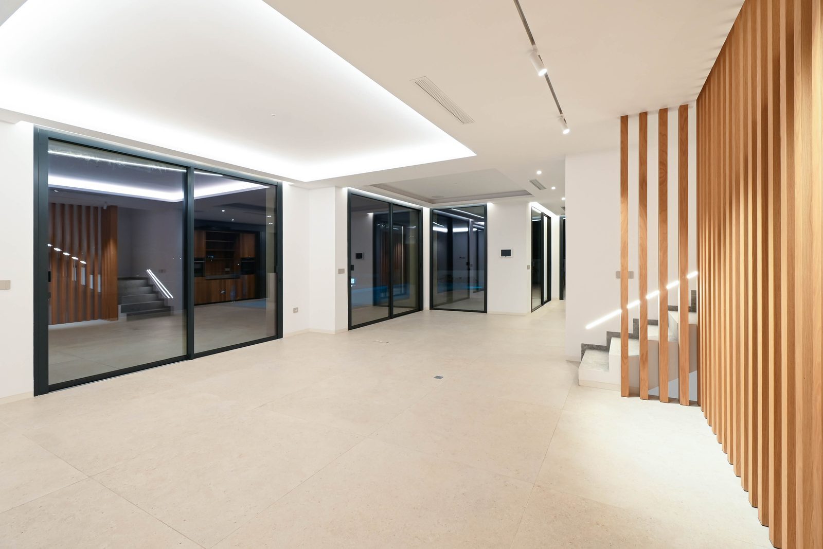 Modern open-plan interior with glass walls, illuminated ceilings and wooden staircase feature in a 4-bedroom villa in Benissa - The Estates