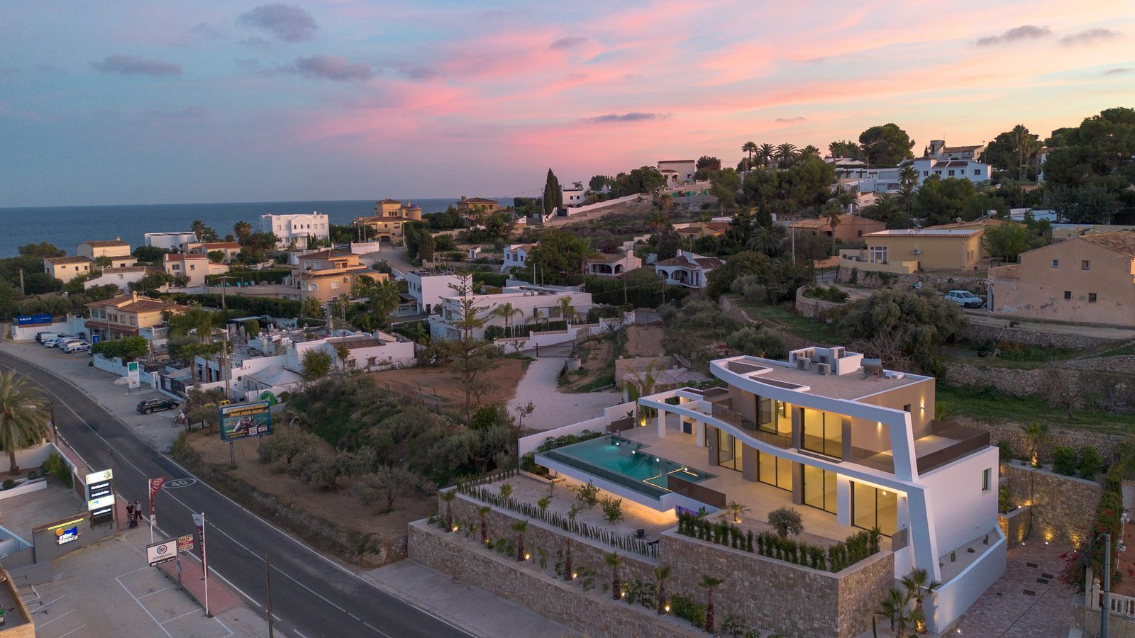 Aerial view of a modern villa with pool and sea views at sunset in La Fustera, Benissa - The Estates