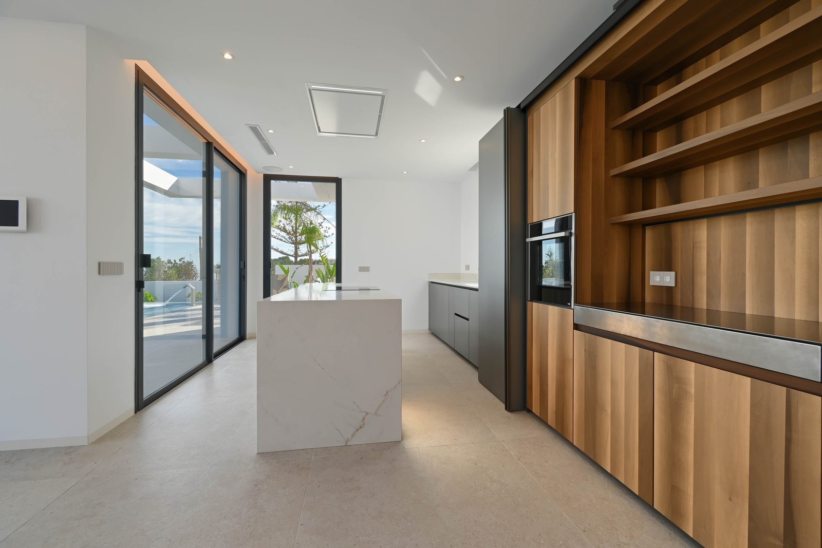 Modern kitchen with island and wood cabinetry of a 4-bedroom villa in Benissa - The Estates
