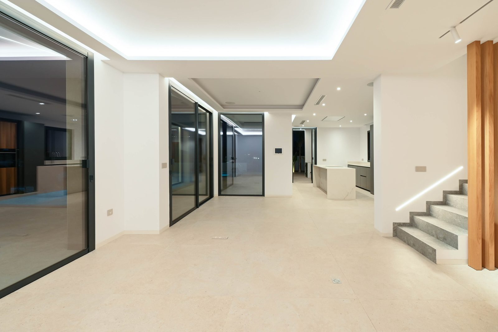 Modern open-plan villa interior with kitchen island, glass doors and staircase in Benissa — a 4-bedroom villa - The Estates