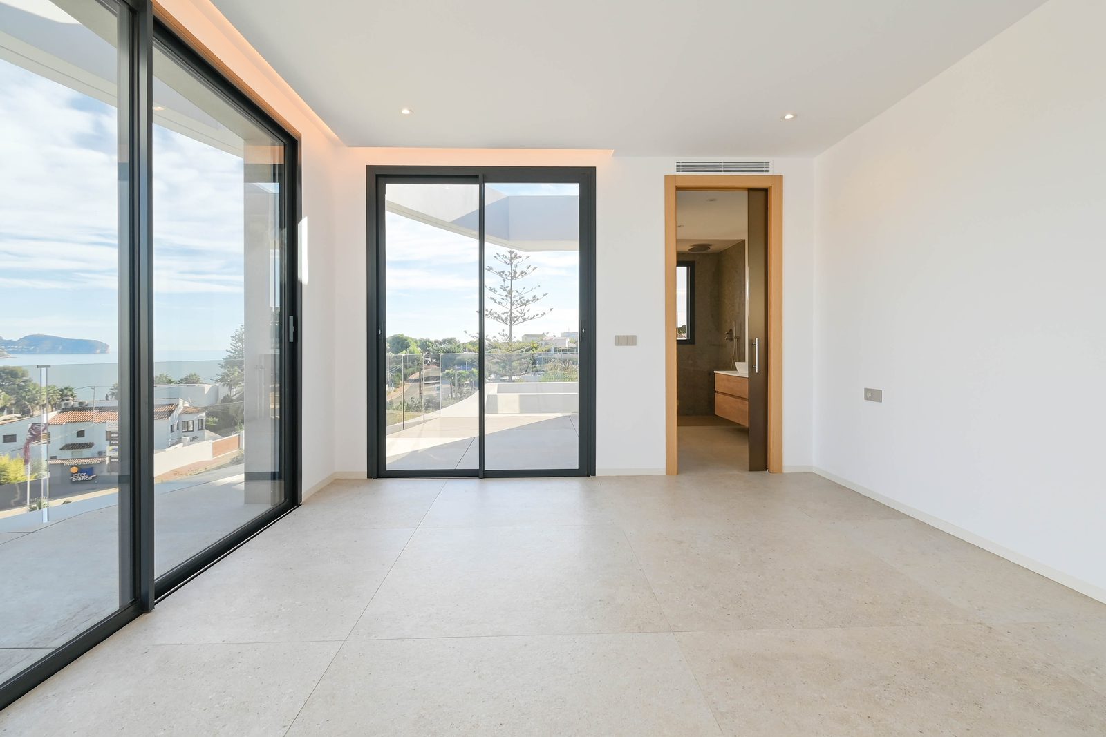 Bright modern bedroom with floor-to-ceiling windows, sea views and an ensuite bathroom in a 4-bedroom villa in Benissa - The Estates