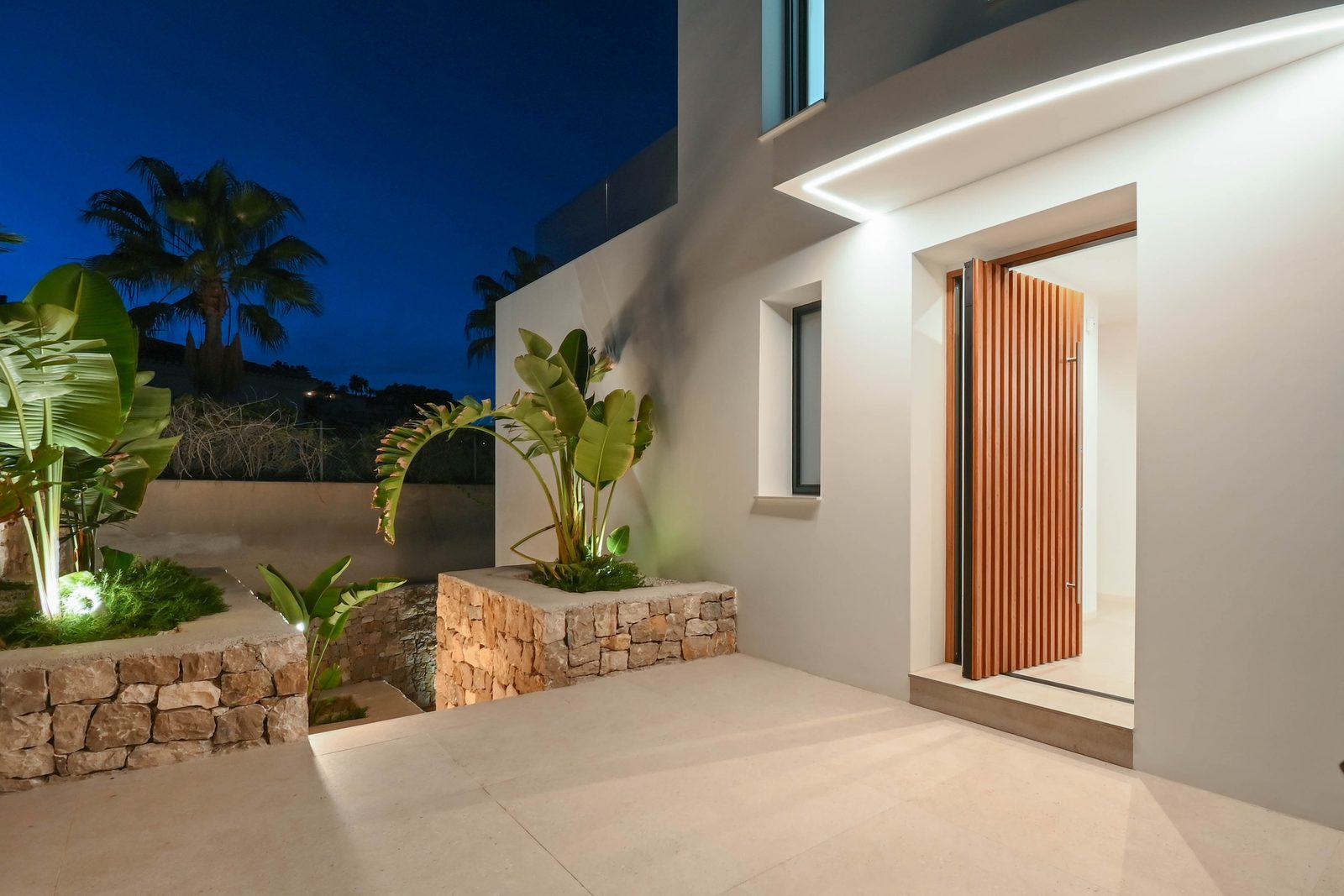 Night-time entrance courtyard with tropical planting and illuminated doorway of a 4-bedroom villa in Benissa - The Estates