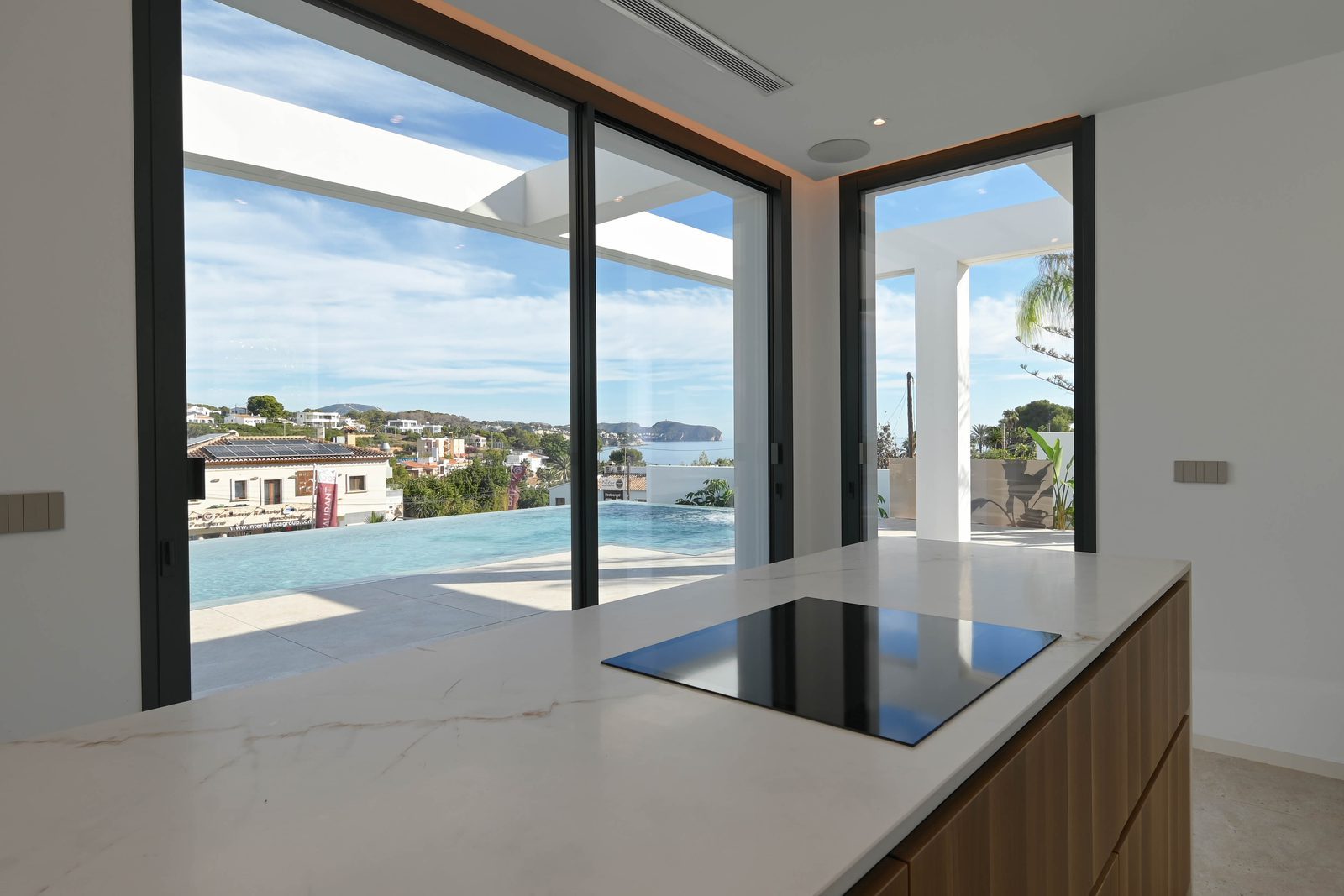 Modern kitchen with island overlooking the pool and sea of a