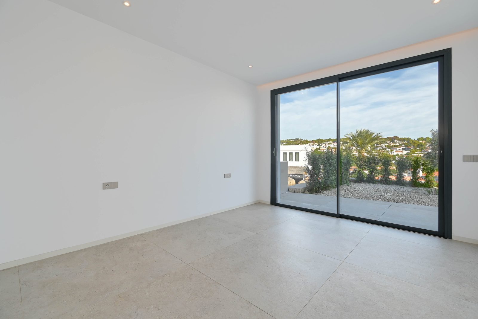 Bright modern room with large sliding glass doors opening to a terrace and hillside views of a 4-bedroom villa