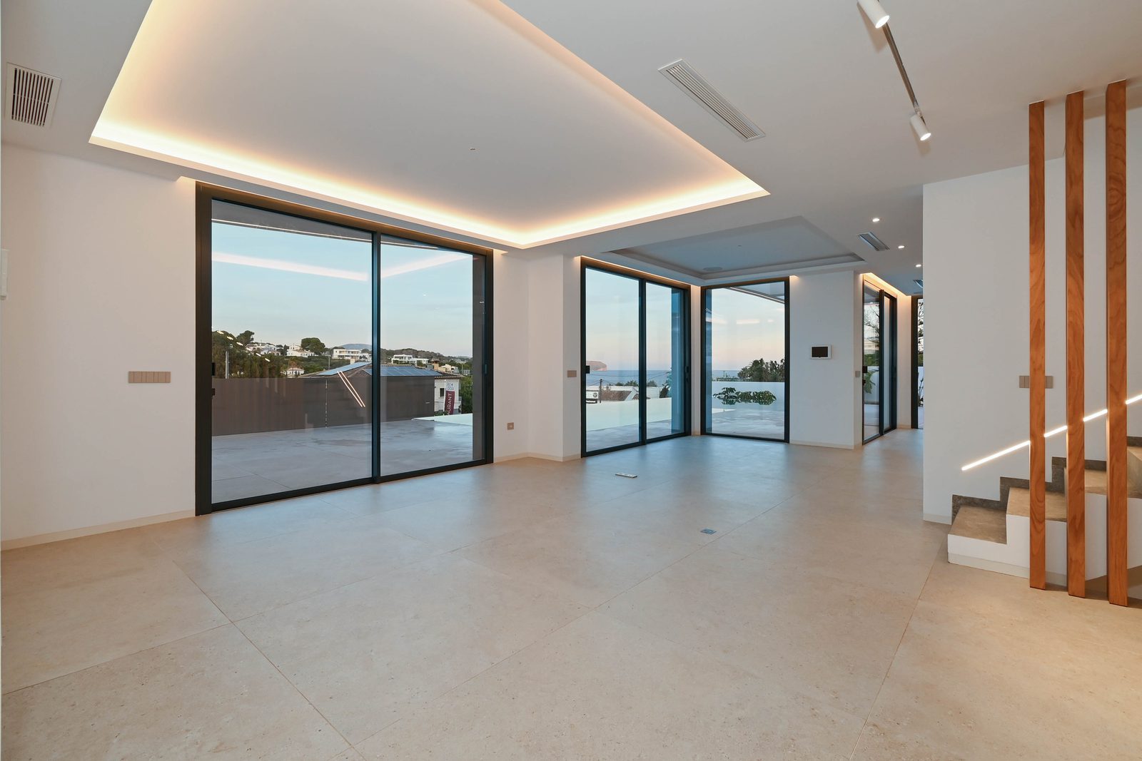 Modern open-plan living room with floor-to-ceiling windows, sea views and staircase in a 4-bedroom villa in Benissa - The Estates