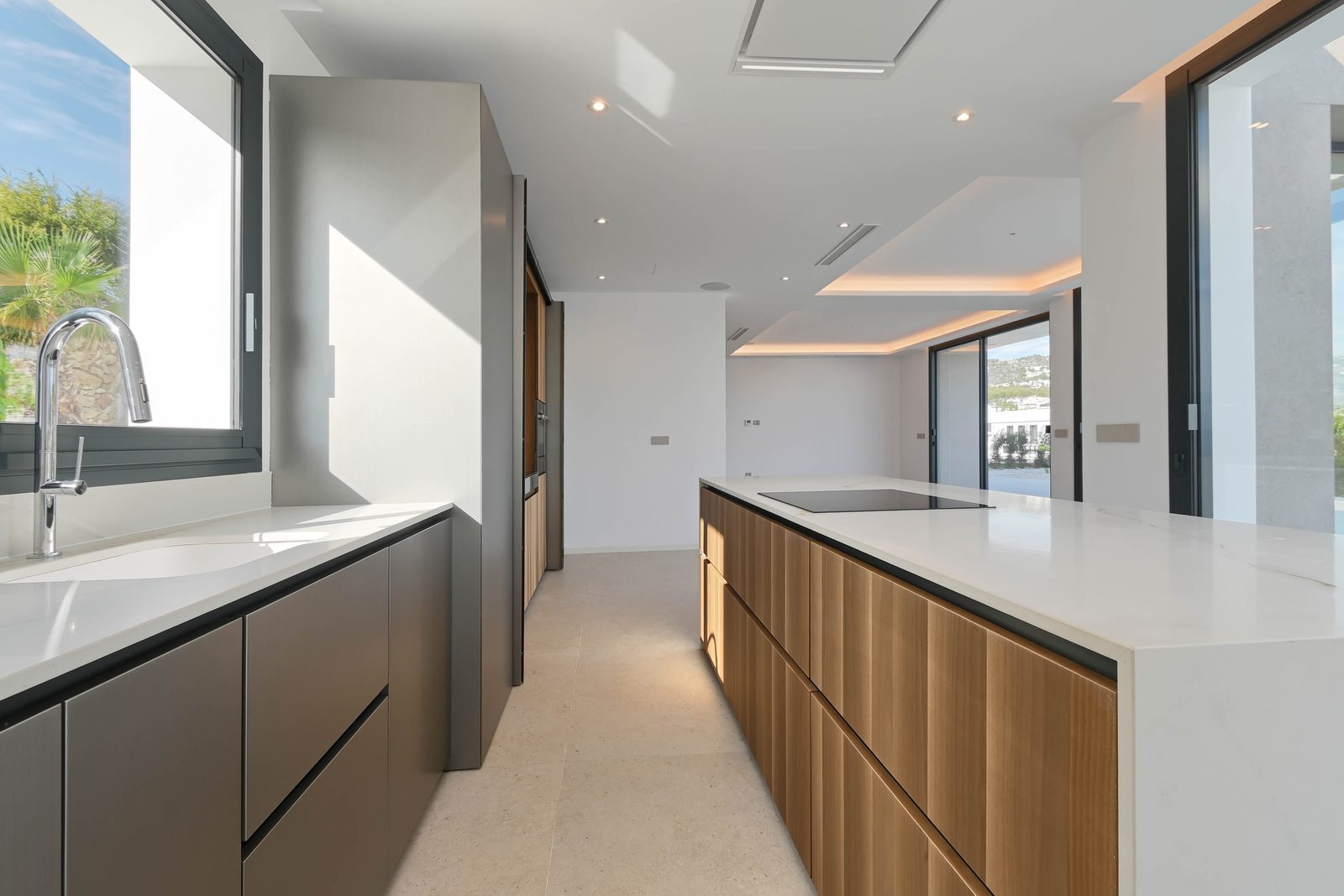 Modern open-plan kitchen with island, wood cabinetry and sea views through expansive windows in a 4-bedroom villa in Benissa - The Estates