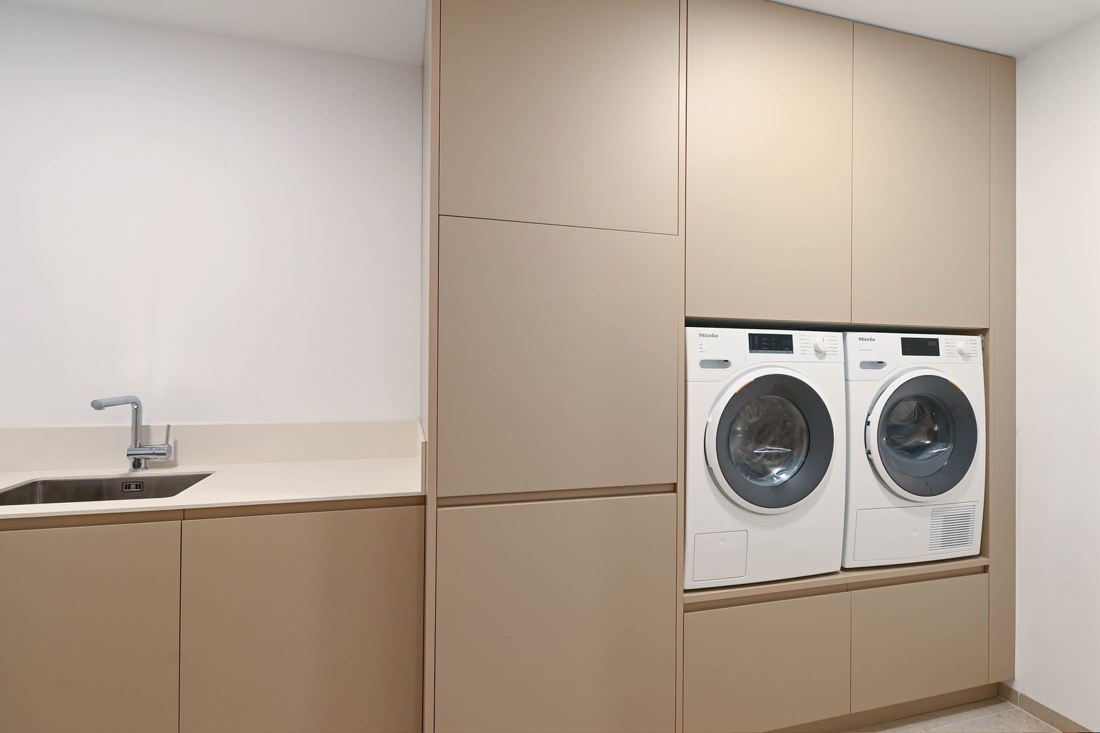 Modern utility room with sink, washer, dryer and fitted cabinetry of a 4-bedroom villa in Benissa - The Estates