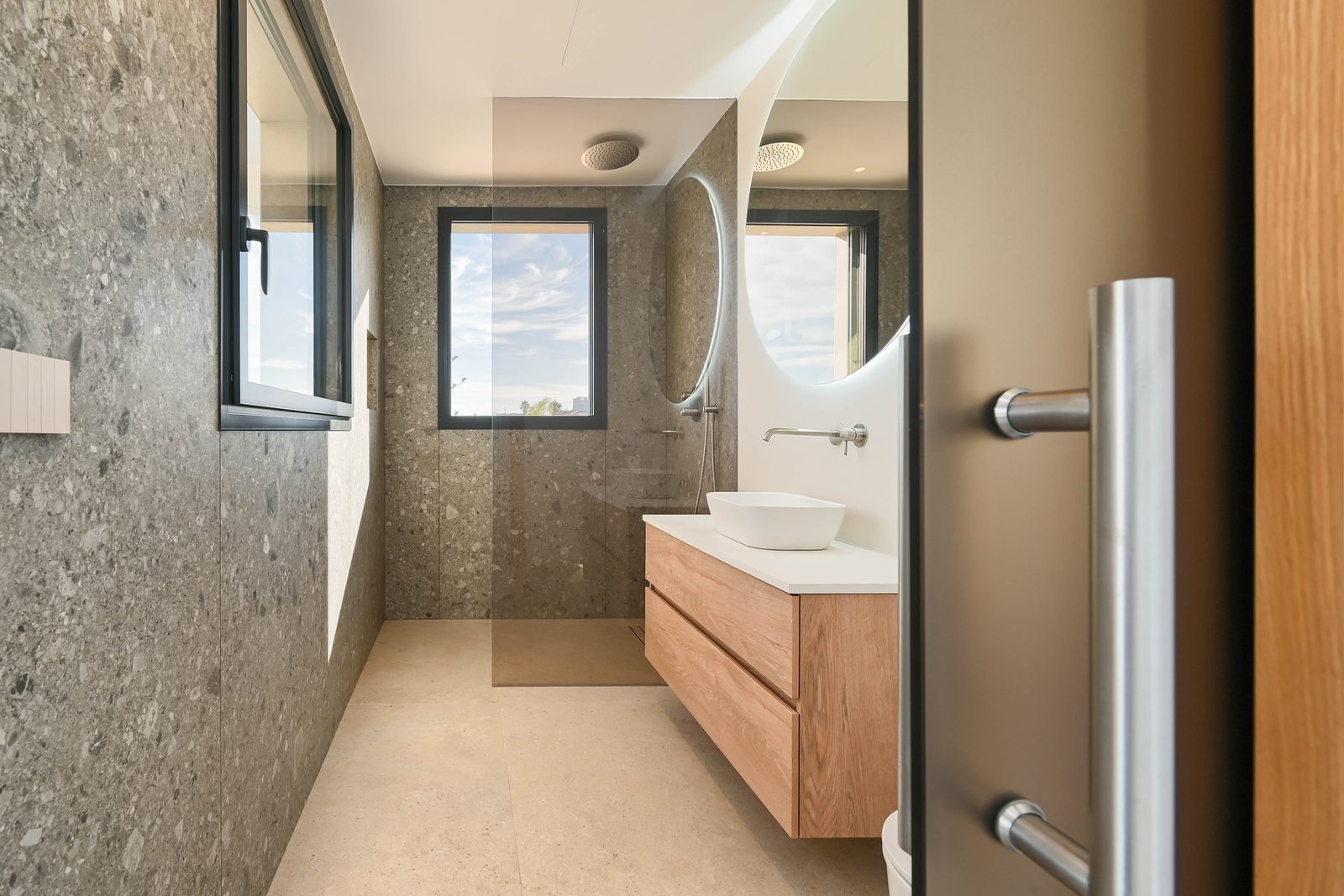 Modern bathroom with walk-in shower, stone walls and wood vanity of a 4-bedroom villa in Benissa - The Estates