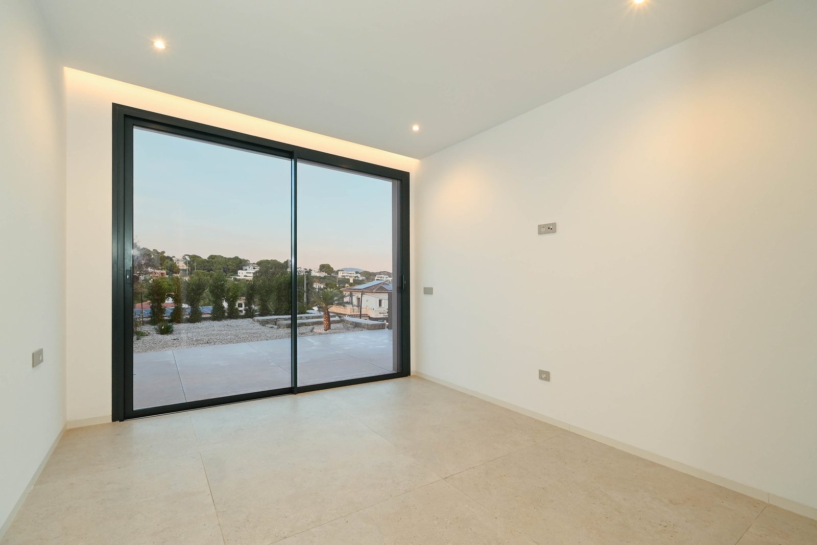 Bright empty room with floor-to-ceiling sliding glass doors and terrace views of the surrounding area in a 4-bedroom villa in Benissa - The
