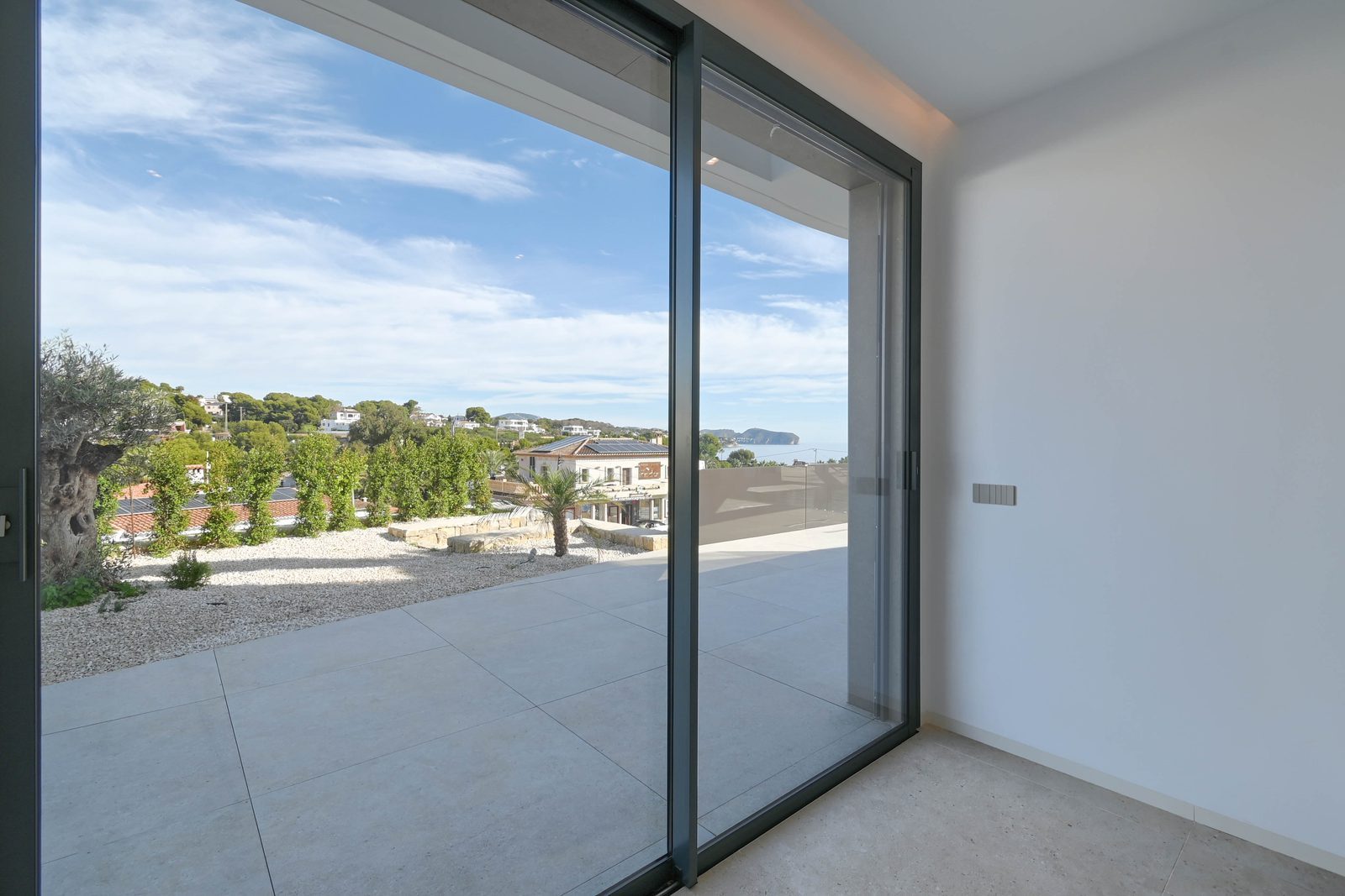 Interior with floor-to-ceiling glass doors opening to a terrace with sea views of a 4-bedroom villa in Benissa - The Estates