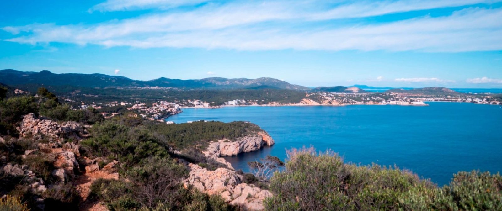 Panoramic coastal view of turquoise bay, rocky shoreline and mountains in Calvia from a 2-bedroom apartment - The Estates