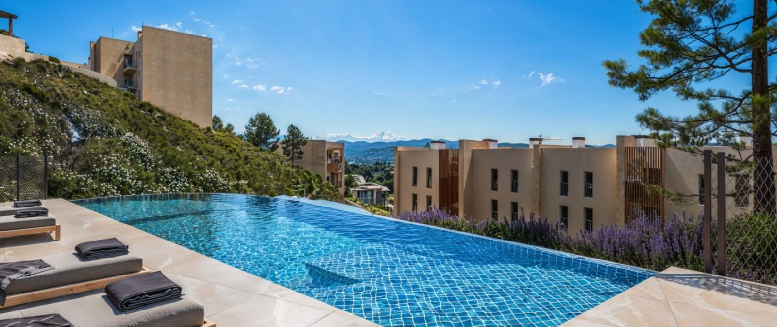 Infinity pool with sun loungers overlooking hillside residences and mountain views at a 2-bedroom apartment in Calvia - The Estates