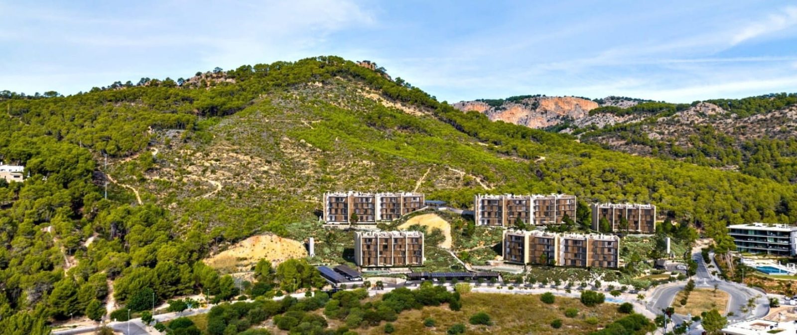 Aerial view of a hillside apartment development surrounded by pine forest in Calvia - The Estates