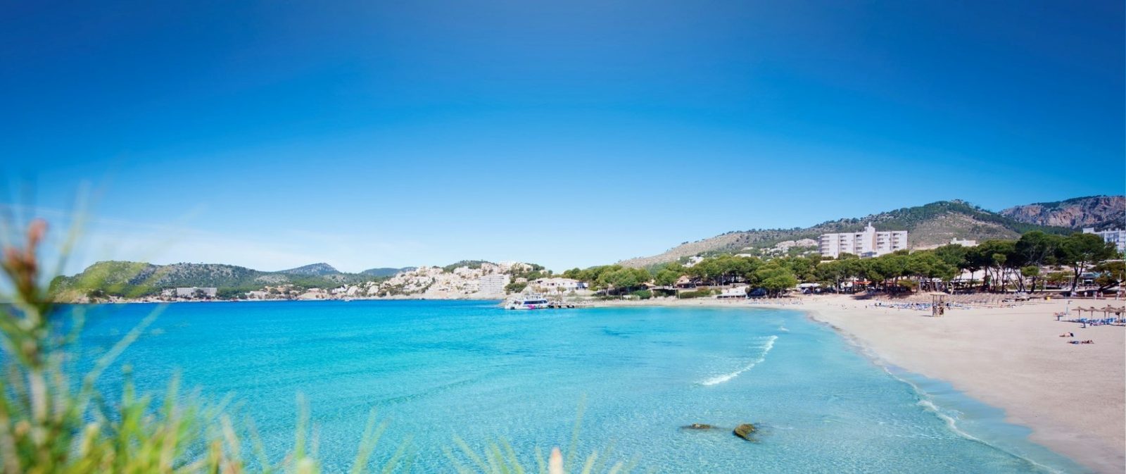 Panoramic view of a turquoise bay, sandy beach and mountain coastline from a 2-bedroom apartment in Calvia - The Estates