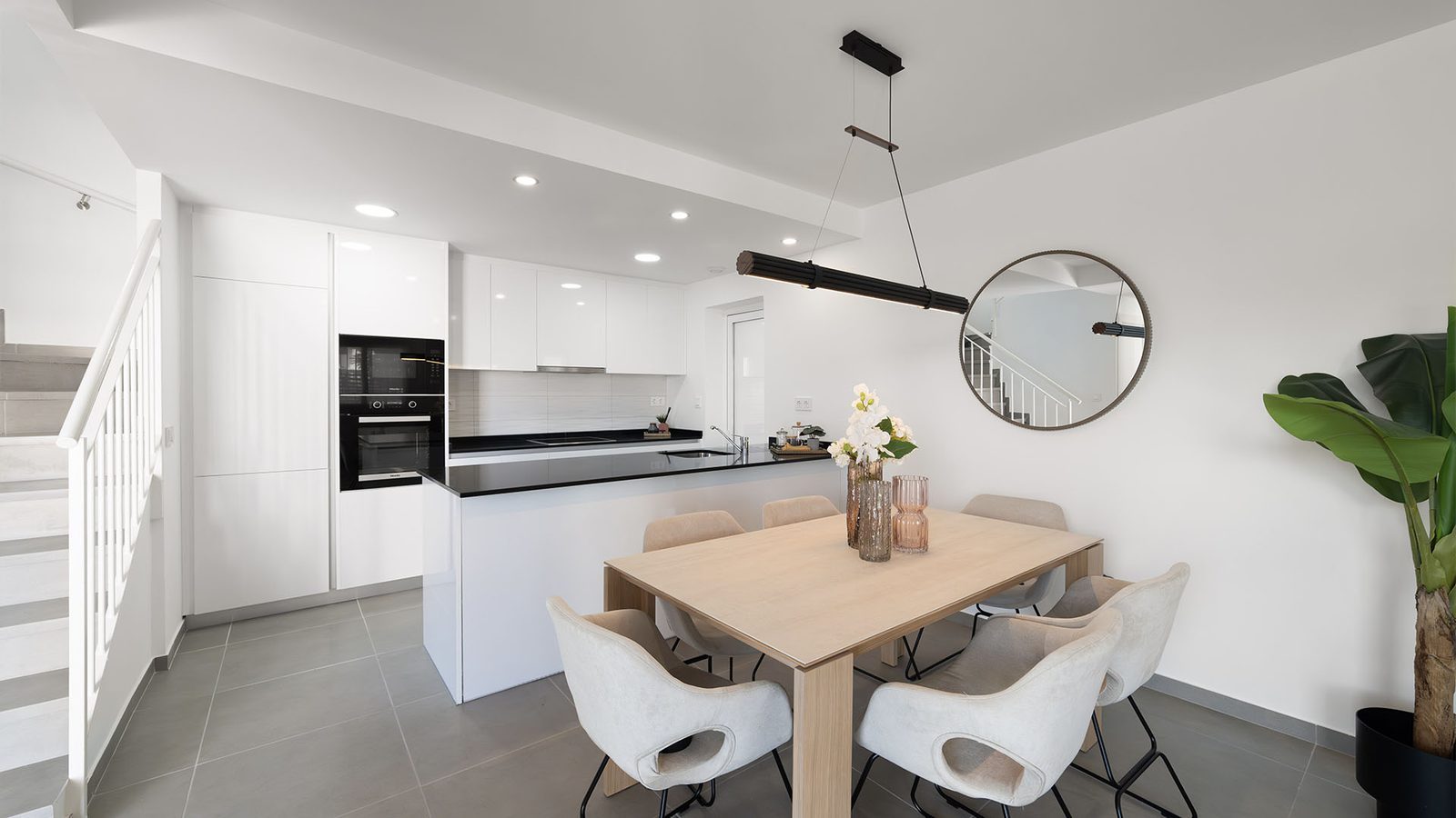 Modern open-plan kitchen and dining area with white cabinetry, island, dining table and staircase in a 3-bedroom semi-detached in Pulpí - The Estates