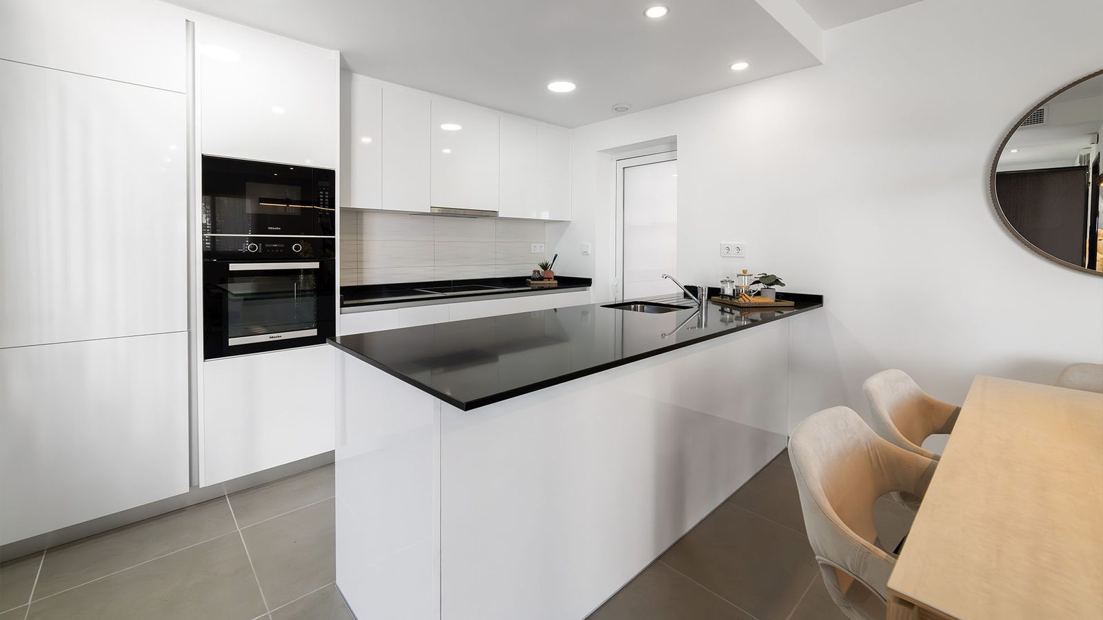 Modern white kitchen with black worktops, central island and adjoining dining area in a 3-bedroom semi-detached in Pulpí - The Estates