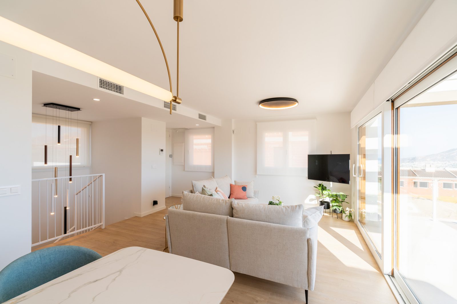 A bright living room with modern decor and large windows overlooking the city - The Estates