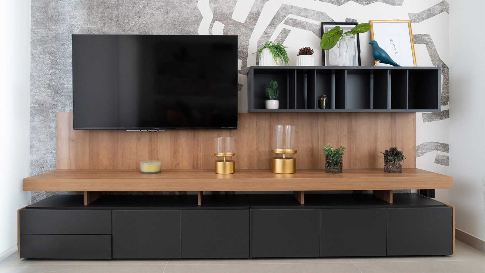 Modern living room TV unit with wood panelling, black cabinetry, shelving and decorative plants in a 3-bedroom apartment in Benidorm - The Estates