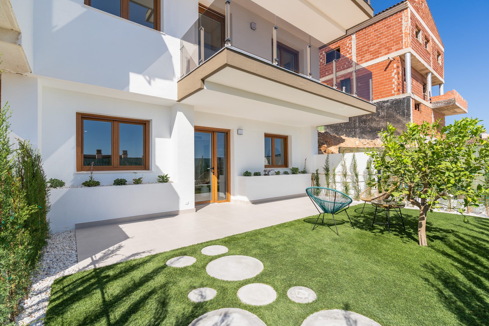 Exterior view of a 4-bedroom townhouse in La Nucía with a garden and seating area - The Estates