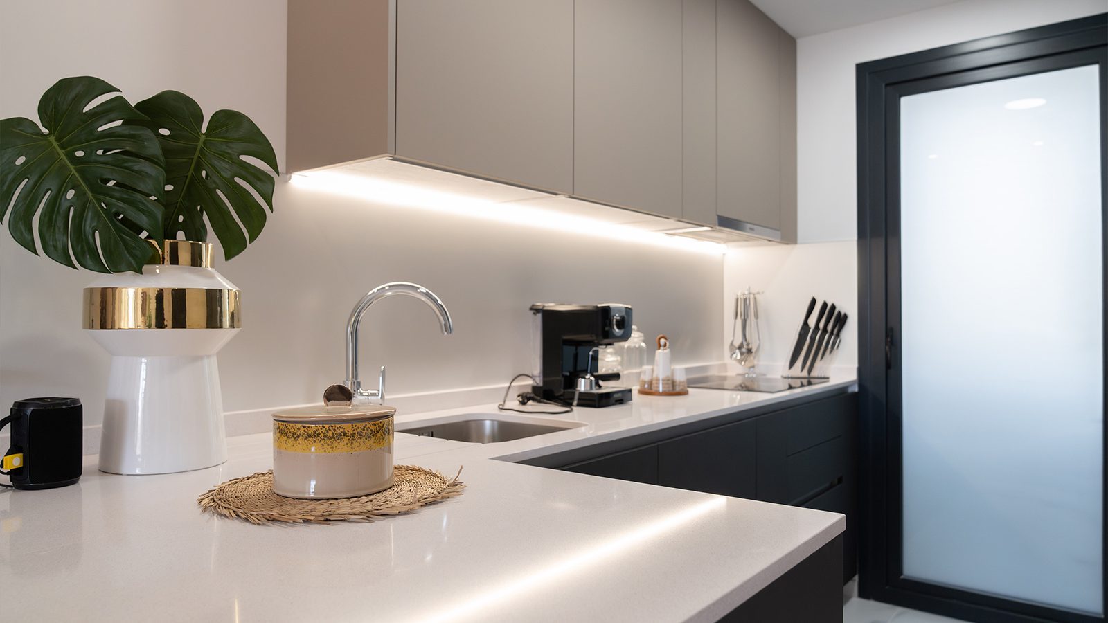 Modern fitted kitchen with island, sink, coffee machine and black-framed door in a 3-bedroom penthouse in Benidorm - The Estates