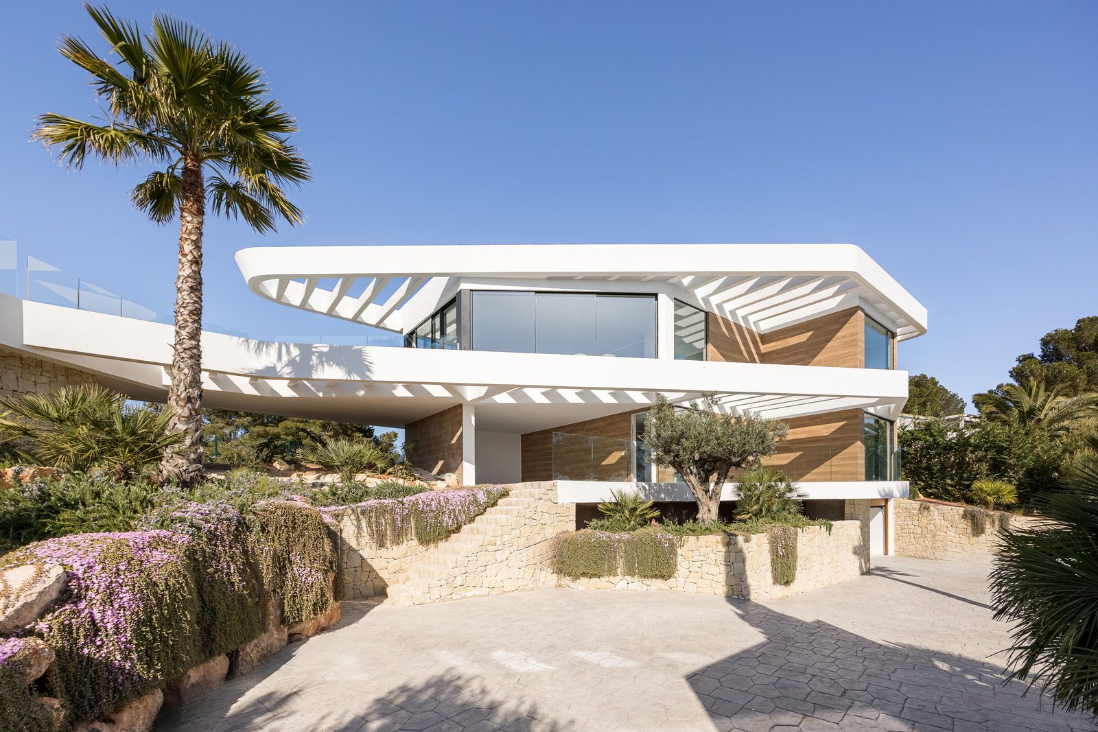 Modern villa exterior with palm trees and sea views of a 5-bedroom villa in Portixol - The Estates