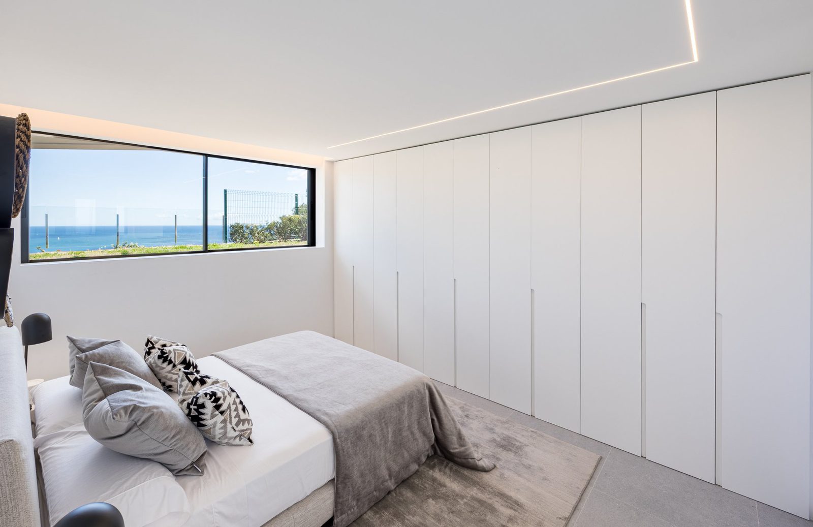 A modern bedroom with built-in wardrobes and sea views in a 5-bedroom villa in Portixol - The Estates