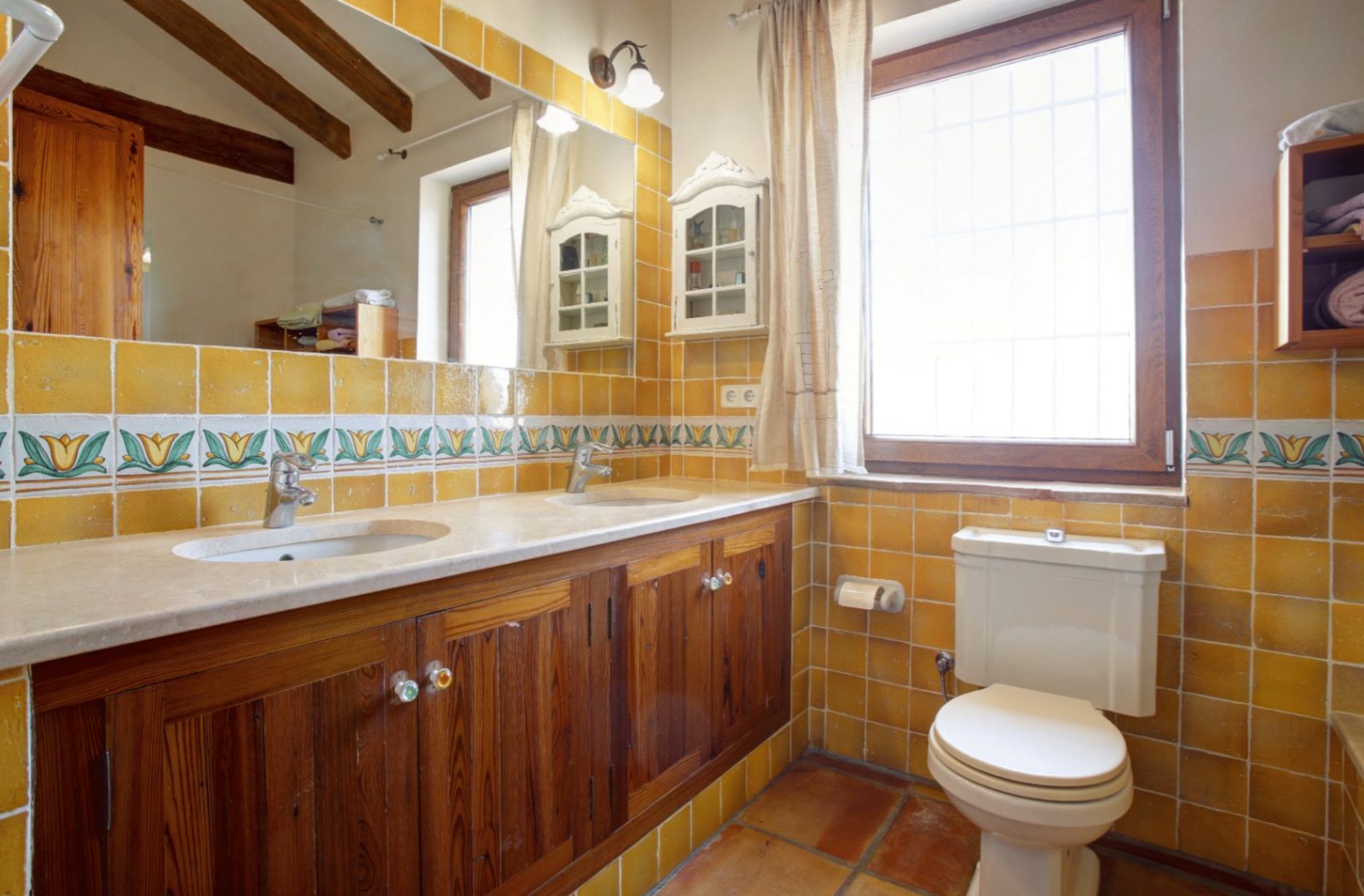 A bright bathroom with tiled walls and wooden cabinetry in a 4-bedroom finca in Moraira - The Estates