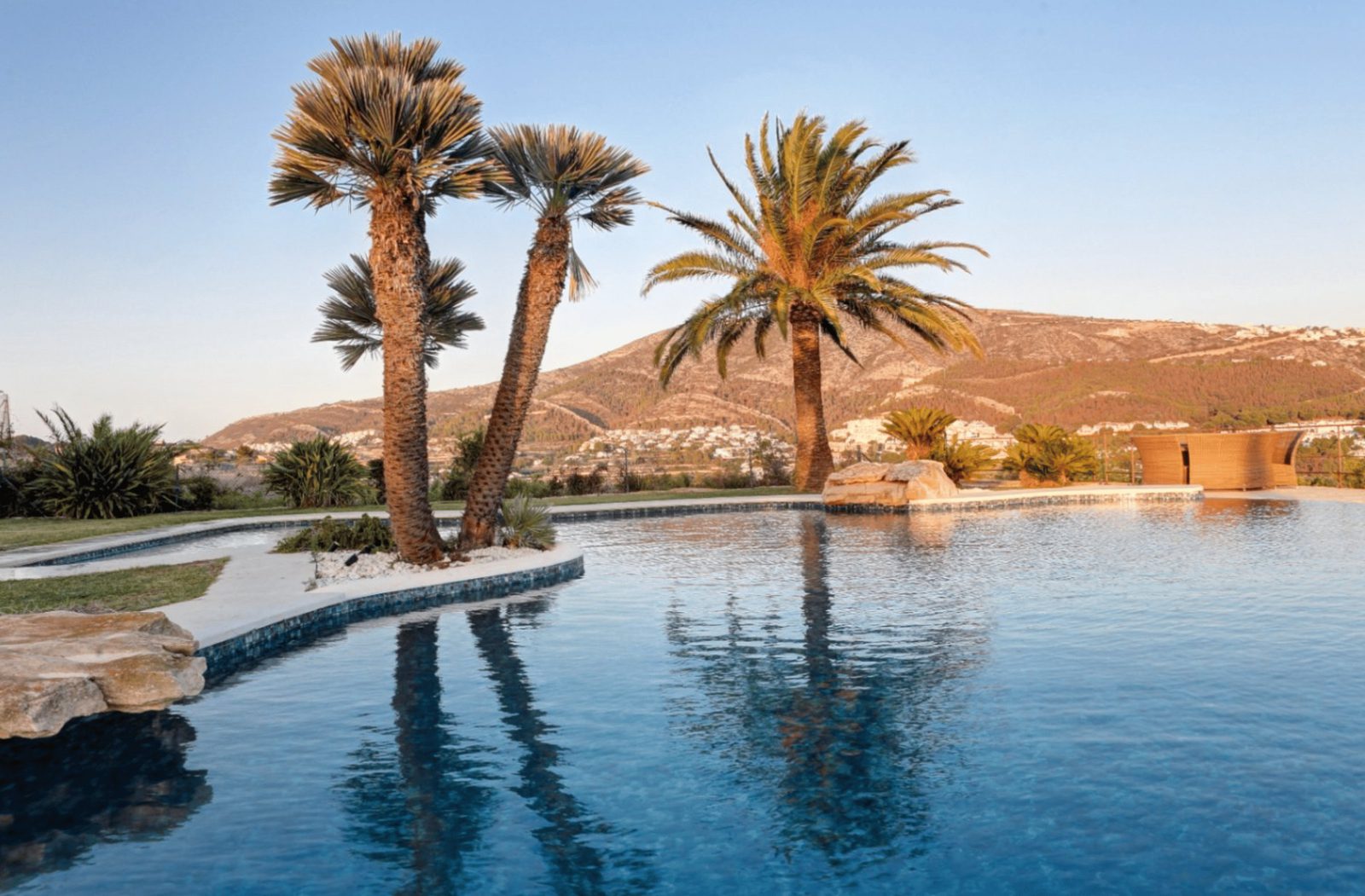 A beautiful pool and palm trees with countryside and sea views of a 4-bedroom finca in Moraira - The Estates