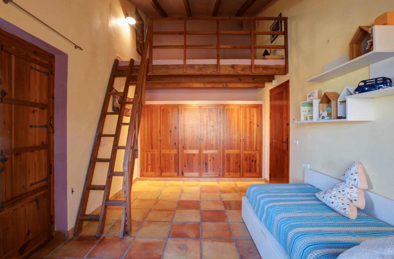 A cozy bedroom with a wooden mezzanine and built-in storage in a 4-bedroom finca in Moraira - The Estates