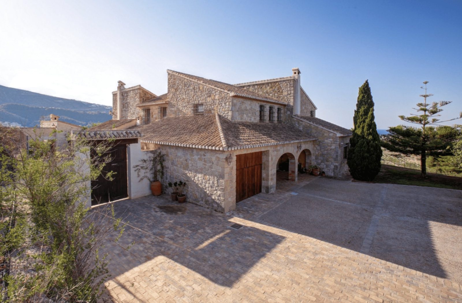 Exterior view of a traditional stone finca with arched porticos in Moraira - The Estates