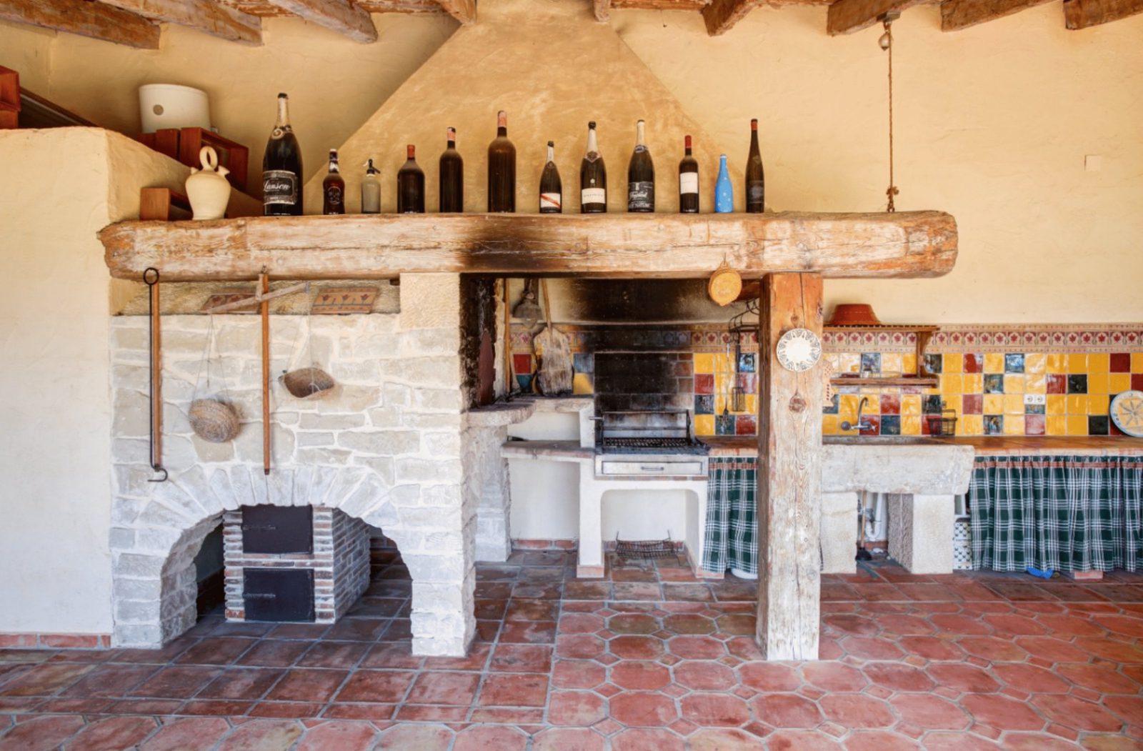 A rustic outdoor kitchen with a fireplace and wine display in a 4-bedroom finca in Moraira - The Estates