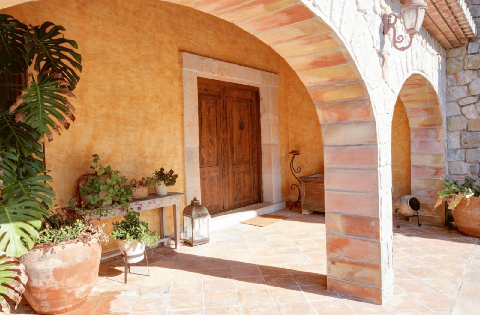 An arched terracotta entranceway with a wooden door and potted plants at a 4-bedroom finca in Moraira - The Estates