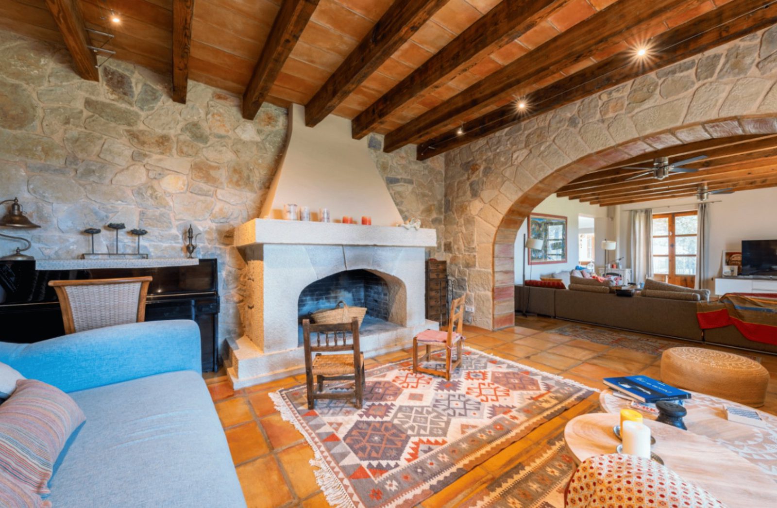Rustic living room with exposed beams and a stone fireplace in a 4-bedroom finca in Moraira - The Estates
