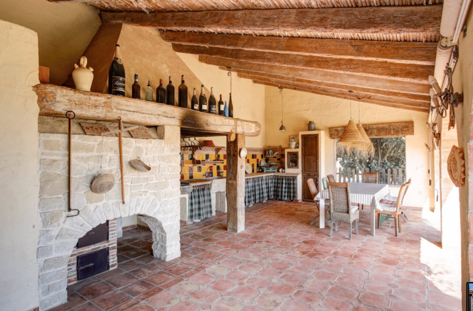 Outdoor kitchen and dining area with a rustic fireplace in a 4-bedroom finca in Moraira - The Estates