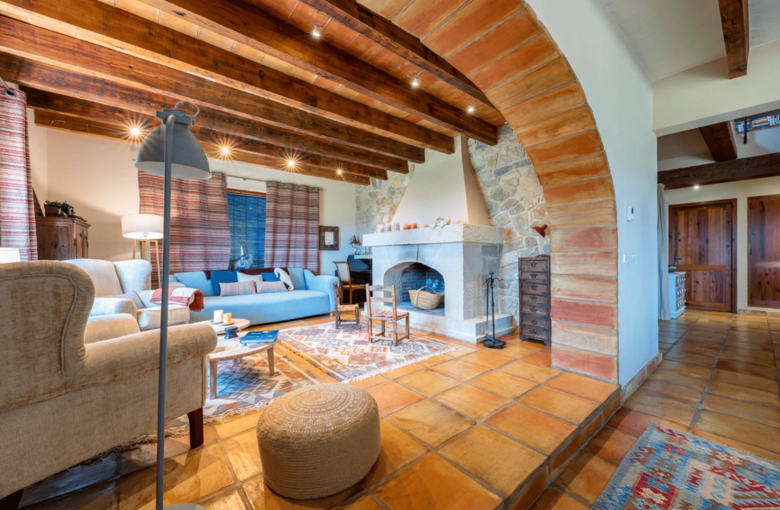 A cozy living room with a stone fireplace and exposed wooden beams in a 4-bedroom finca in Moraira - The Estates