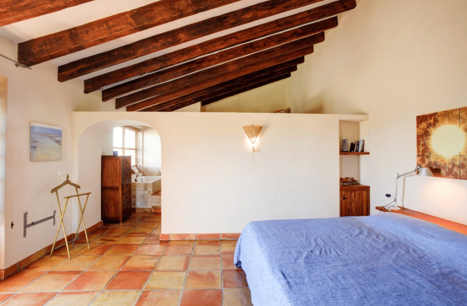 A bright bedroom with exposed wooden beams and terracotta tile flooring in a 4-bedroom finca in Moraira - The Estates