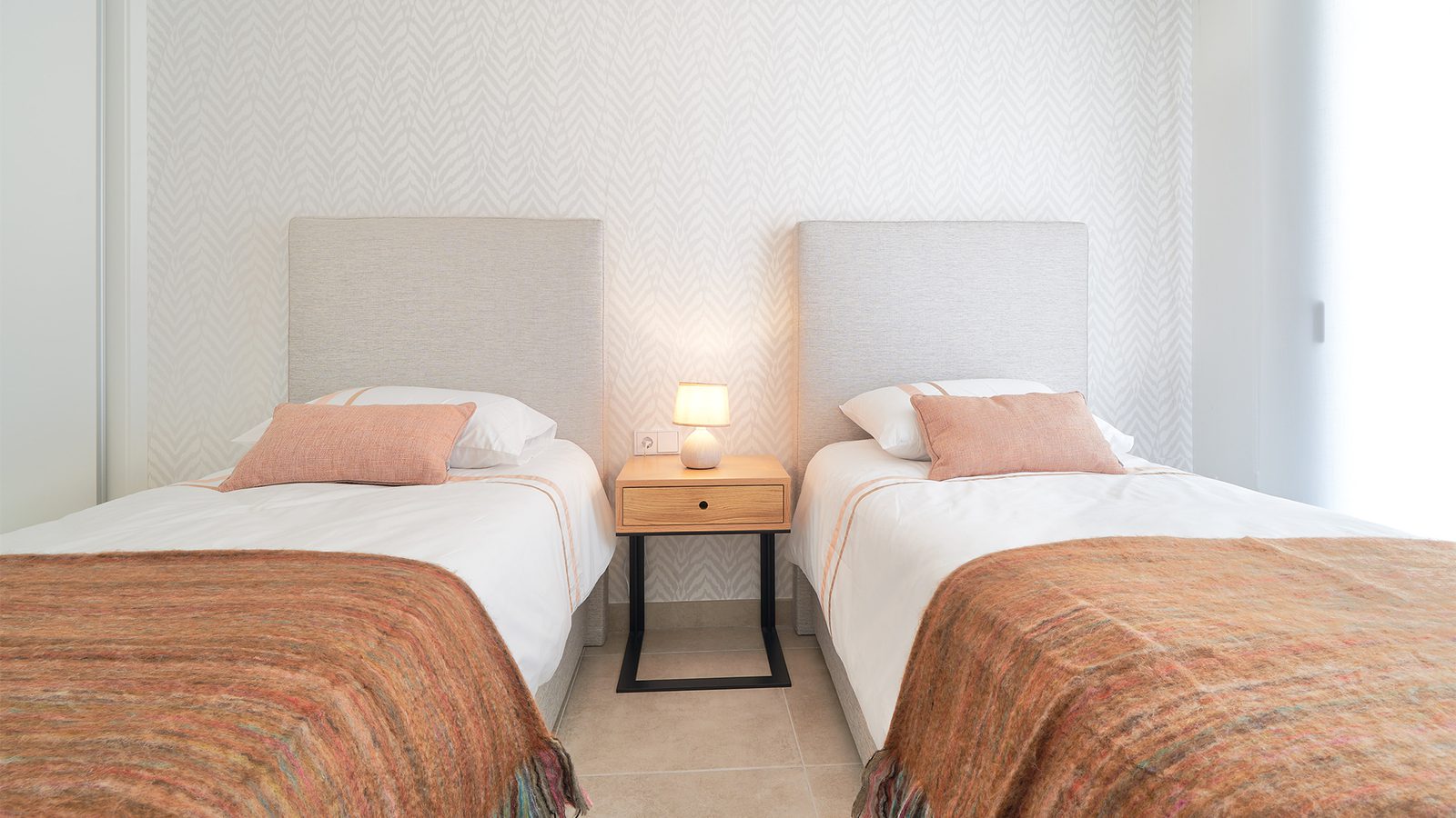 Stylish twin beds in a bedroom of a 3-bedroom apartment in Estepona - The Estates