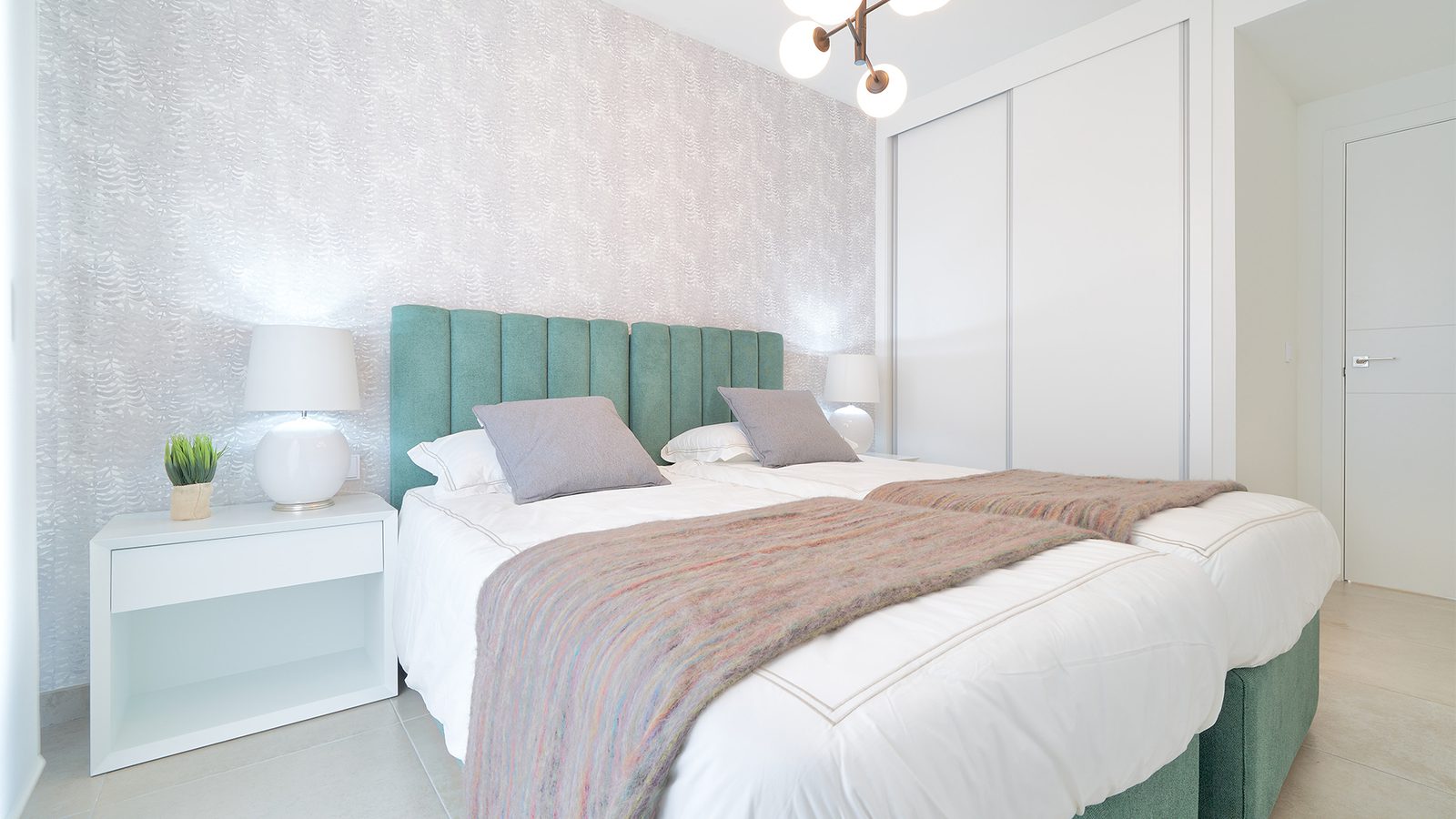 A stylish bedroom with a green headboard and modern decor in a 3-bedroom apartment in Estepona - The Estates